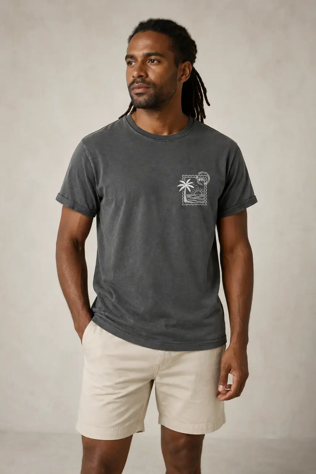 T-shirt vieilli homme gris anthracite délavé avec un timbre palmier 971 avec mer et soleil imprimé en blanc, porté par un homme en studio dans une lumière naturelle